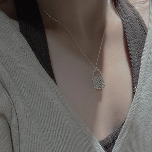 Gros plan du collier avec pendentif sac perlé en argent S925 sur un mannequin en maille