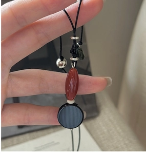 Macro view of vintage S925 silver necklace with red agate bead and black round pendant