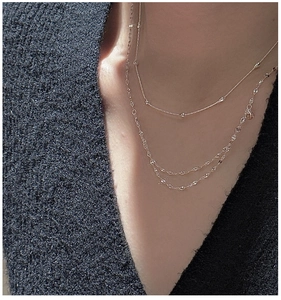 Close-up of layered silver S925 sterling silver necklaces worn on a black knit sweater