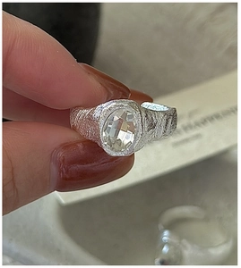 Detail of S925 silver ring with oval zircon and handcrafted textured metal finish