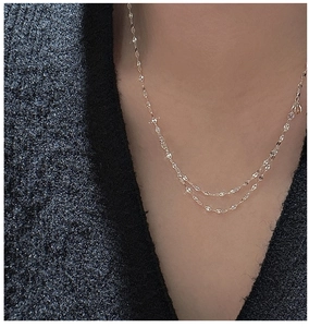 Detailed view of layered gold silver necklace with textured links on model's neckline