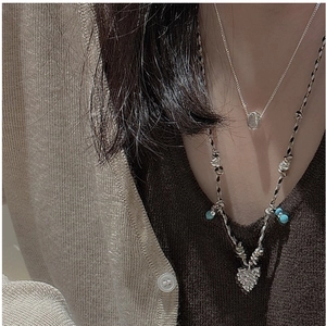 Détail du pendentif feuille en argent S925 et perle bleue sur un collier tissé