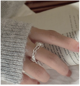 Close-up of S925 sterling silver woven twist ring styled with a vintage aesthetic
