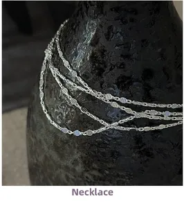 Vue macro d'un collier en argent S925 à facettes disposé sur un vase en céramique