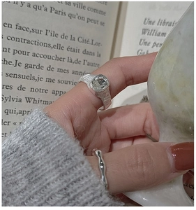 Macro detail of S925 silver textured ring set with oval zircon on a vintage book background