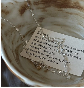 Detailed shot of sparkling S925 sterling silver chain with citrine on marble ceramic bowl