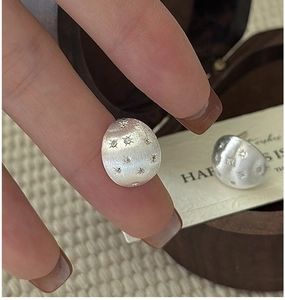 Detail view of S925 sterling silver star stud earrings with a brushed metallic texture