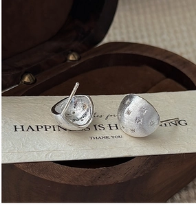 Macro view of matte brushed S925 silver star earrings on a vintage paper card