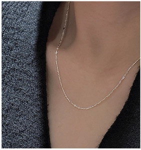 Gros plan d'un collier fer à cheval en argent S925 porté par un mannequin en tweed gris