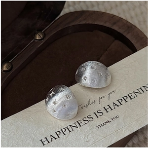 Macro detail of S925 sterling silver star-engraved earrings with matte brushed finish