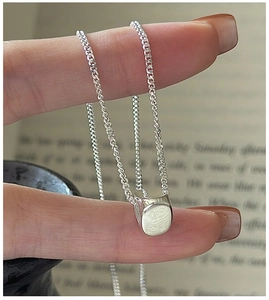Close-up of minimalist S925 sterling silver chain with a geometric triangle pendant