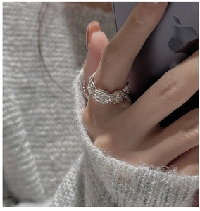 Detailed close-up of a S925 silver star-themed ring with woven texture on index finger