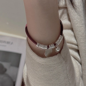 Red braided S925 sterling silver rope bracelet with round charms worn by a model