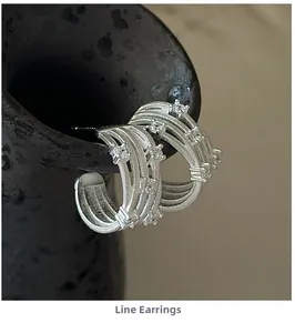 Detailed close-up of S925 silver cross earrings with zircon pavé on a black vase