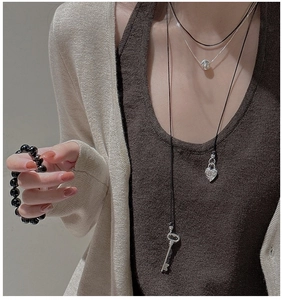 Détail de colliers superposés en argent S925 avec pendentifs cœur et clé