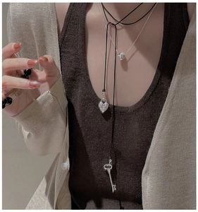 Gros plan de colliers superposés en argent S925 avec pendentifs cœur et clé sur modèle