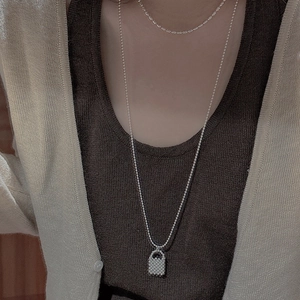 Detail of silver S925 long beaded necklace with mini handbag pendant worn by a model