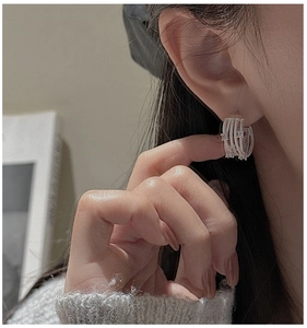 Close-up of S925 silver cross earrings with zircon stones worn by a model