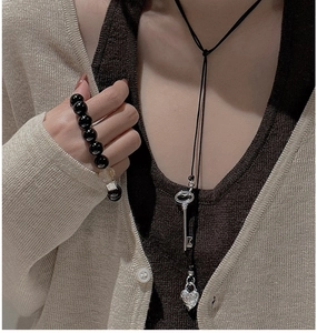 Détail du pendentif clé et cadenas en argent S925 sur une longue chaîne de pull