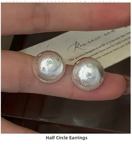 Macro detail of S925 sterling silver star earrings with a brushed texture and semi-sphere design