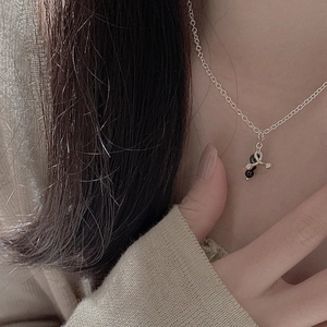 Silver necklace with irregular pendant and black bead shown on a model's neck