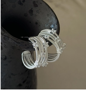 Macro shot of silver-colored multi-layer textured hoop earrings with white zircon accents