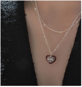 Macro detail of S925 silver layered necklace with red and black heart 'LOVE' pendant