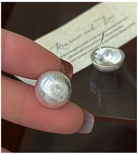 Detail of S925 sterling silver brushed dome earrings with engraved star pattern motifs