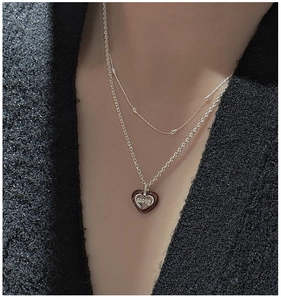 Detail of a double-layered S925 silver necklace with a heart pendant and LOVE engraving
