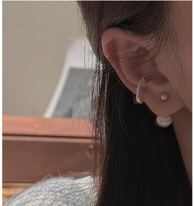 Close-up of S925 sterling silver ear cuffs and studs set with pearls on a model ear