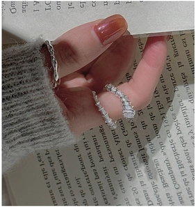 Detail of stacked S925 sterling silver rings featuring a wavy band and a square diamond ring