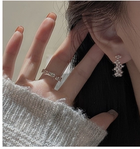 Gros plan de boucles d'oreilles perles en argent S925 et bague texturée sur mannequin