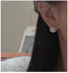 Close-up of pearl texture stud earring with star engraving on a female model