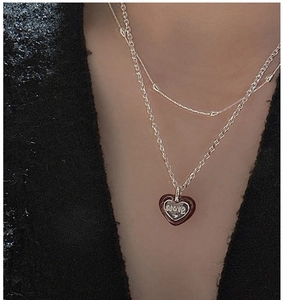 Macro view of a silver double-layered necklace with a heart pendant engraved with LOVE