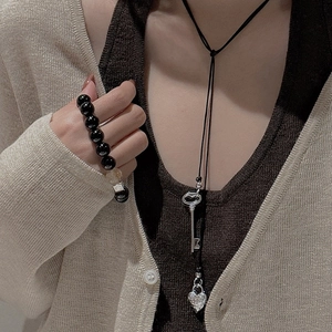 Pendentif cœur et clé en argent S925 porté sur un gilet en maille beige pour femme
