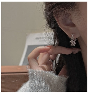 Détail des boucles d'oreilles à perles argentées et bague ondulée sur mannequin avec lumière