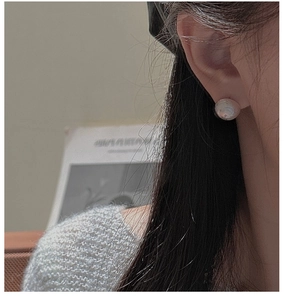 Detail of elegant pearl texture stud earring with fine gold accents on model