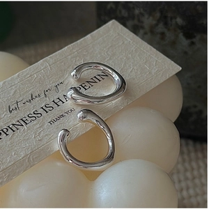 Macro detail of irregular fluid silver ear cuffs on a minimalist gift card background