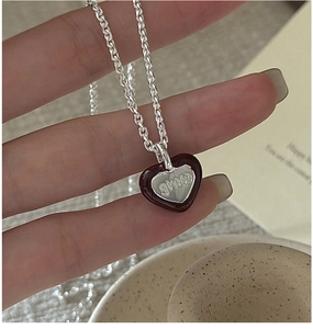 Detailed macro view of silver heart necklace with red enamel and LOVE engraving