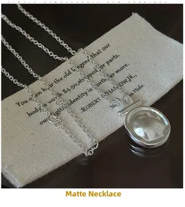 Macro detail of matte S925 sterling silver oval pendant on textured linen cloth