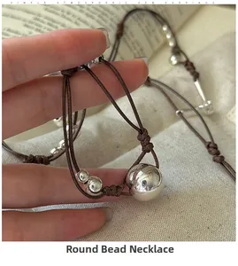 Gros plan de perles en argent S925 et d'une corde tressée sur un fond de livre vintage