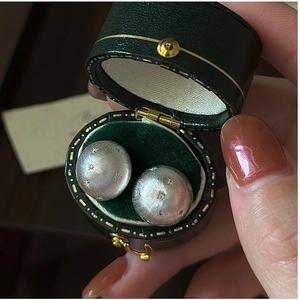 Close-up of S925 silver star earrings with brushed texture in a green velvet jewelry box