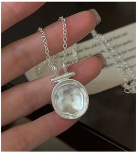 Detailed view of an S925 sterling silver necklace with a textured round hammered pendant