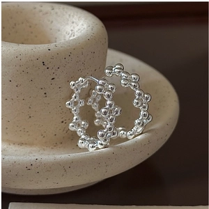 Détail macro de créoles en argent sterling S925 avec un design perlé texturé unique