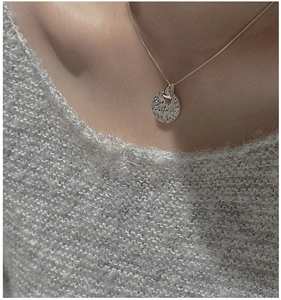 Macro detail of hammered silver circular pendant on minimalist snake chain necklace