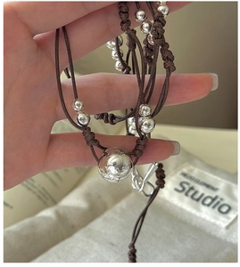 Vue détaillée des perles argentées sur un collier en corde marron tressée à la main
