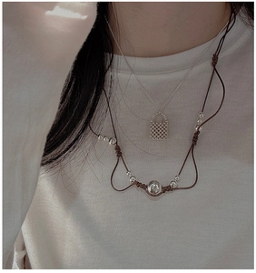 Détail de colliers superposés en argent S925 avec breloque tissée et perles brunes