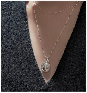 Detail of layered S925 silver pendant necklace set on a black textured sweater