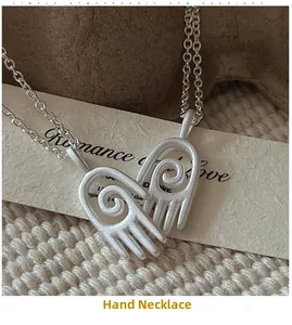 Détail macro du collier en argent S925 avec pendentif mains formant un cœur mat
