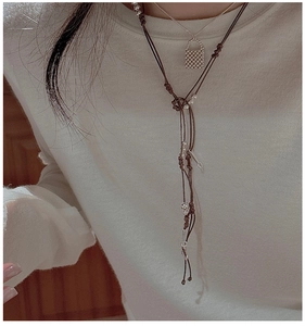 Détail du collier en argent S925 avec cordon tressé et perles sur pull en maille